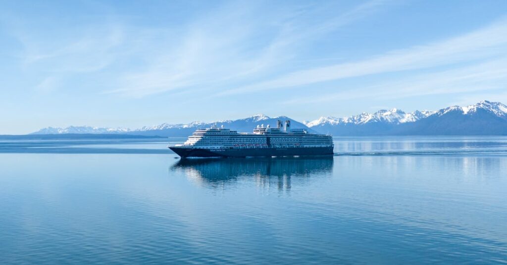 A cruise ship sails through serene waters with snowcapped mountains in the background in Hoonah, Alaska.