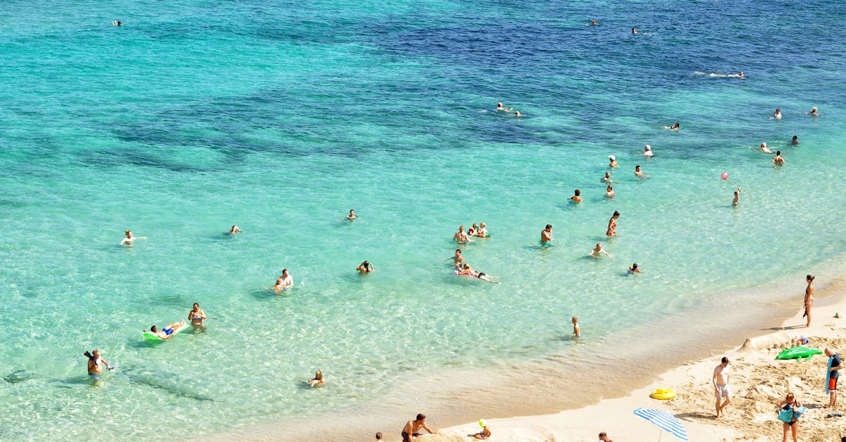 People enjoying a sunny day at a beautiful beach in Mallorca, Spain, with turquoise water and sandy shores.
